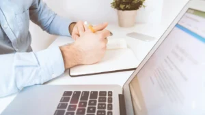 Healthcare professional taking notes beside a laptop while reviewing billing information
